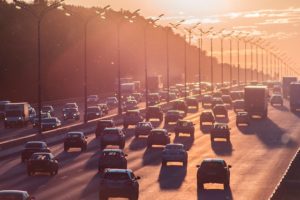 Cars driving along a highway at sunrise.