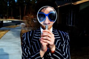 Searcher in a pinstripe suit and blue glasses.