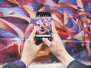 Person takes photo of a mural for Instagram.